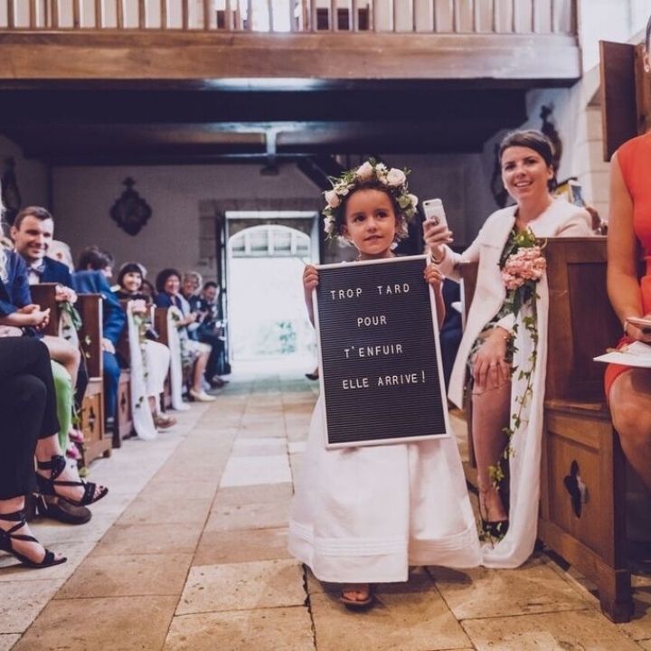 Photo d'une petite fille en robe blanche qui tient une affiche